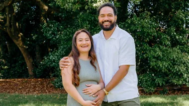 Mikey Falesiu with his hands on his wife's pregnant belly