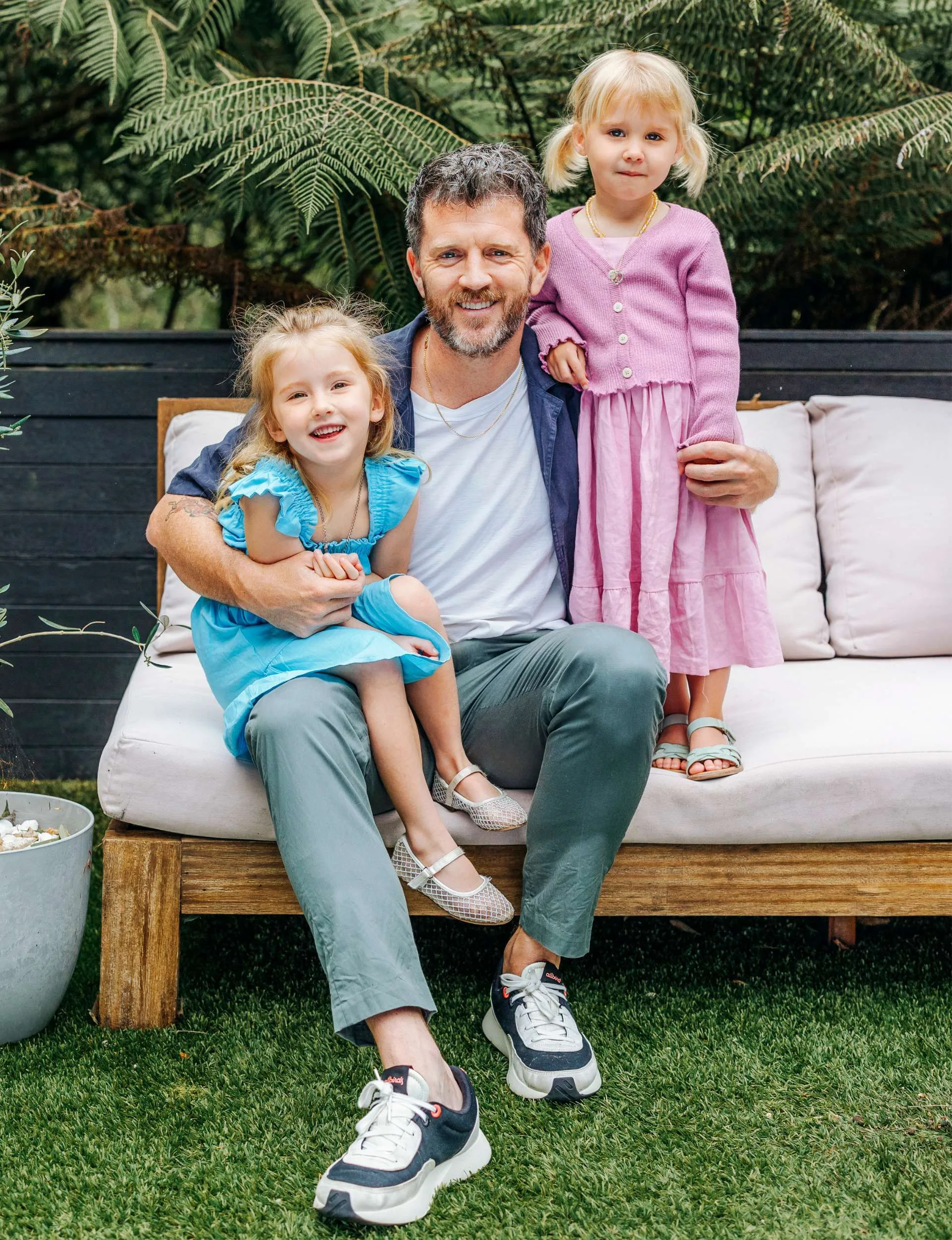 Ryan O'Kane sitting on an outdoor couch with his daughters