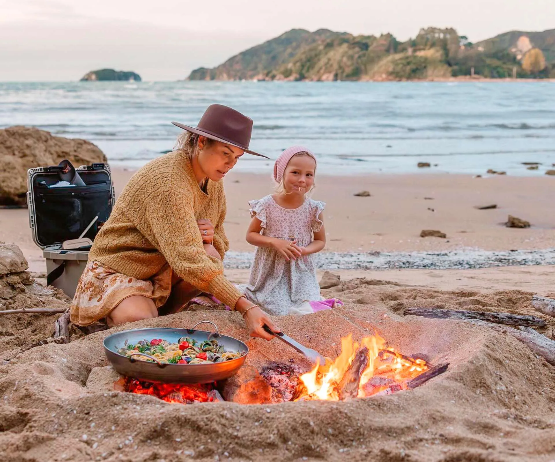 The family cooking over a bonfire on the beach while they travel