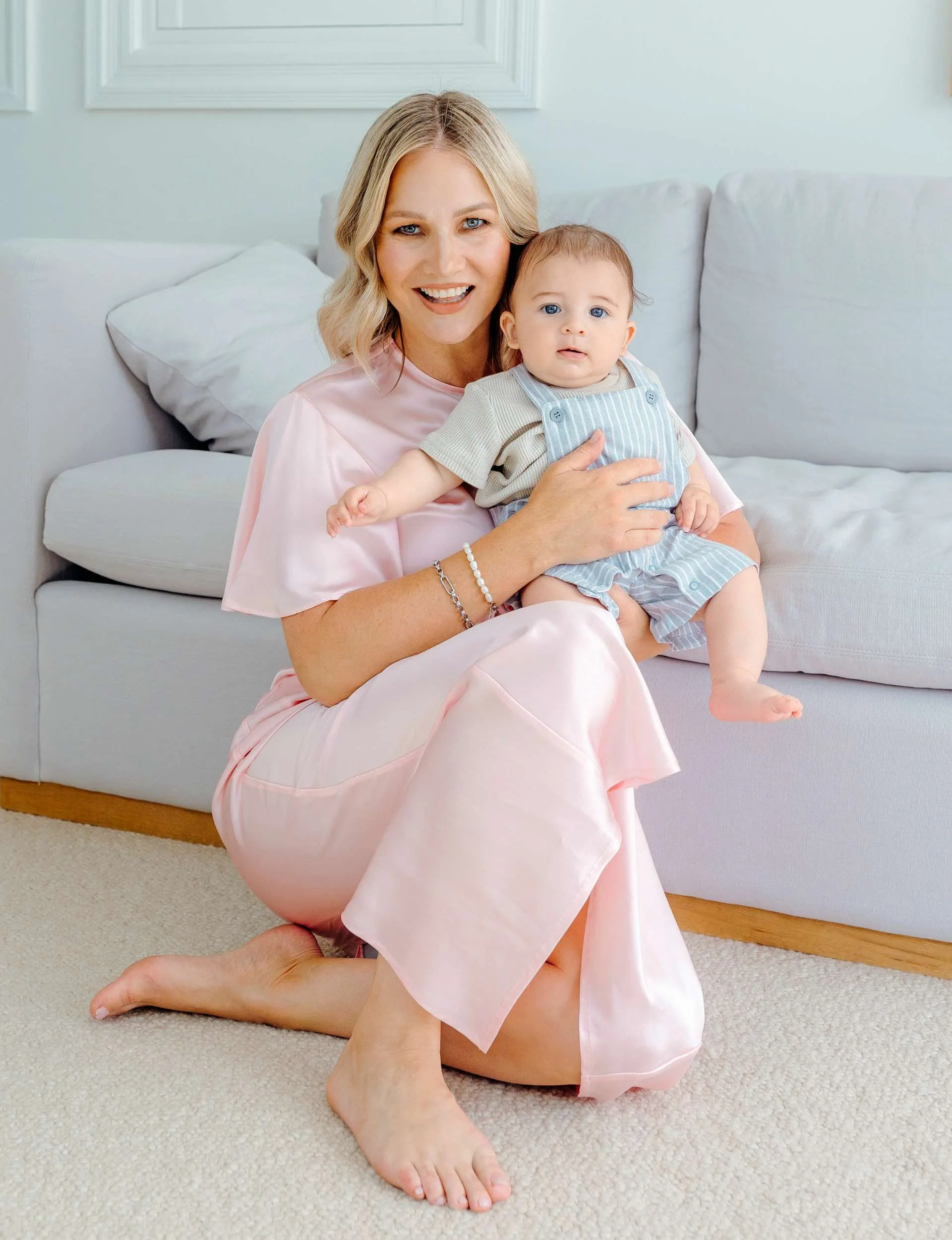 Hayley Holt sitting on the ground holding baby Kingston
