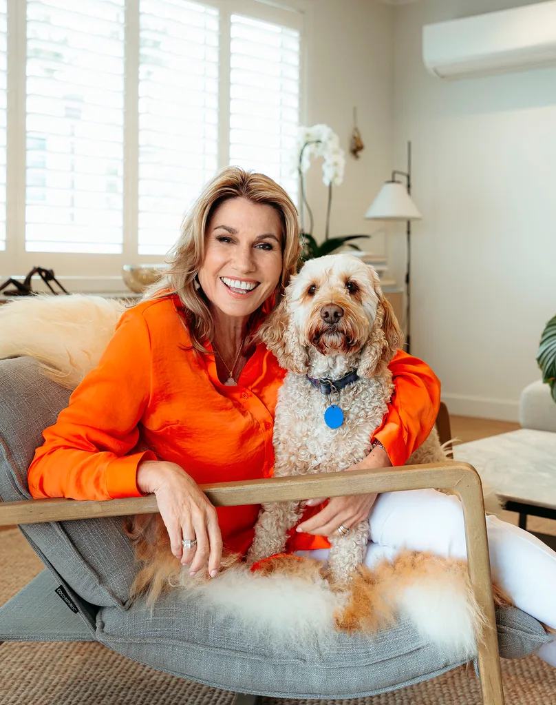 Jayne Kiely sitting on chair with her dog Frank in light bright lounge space