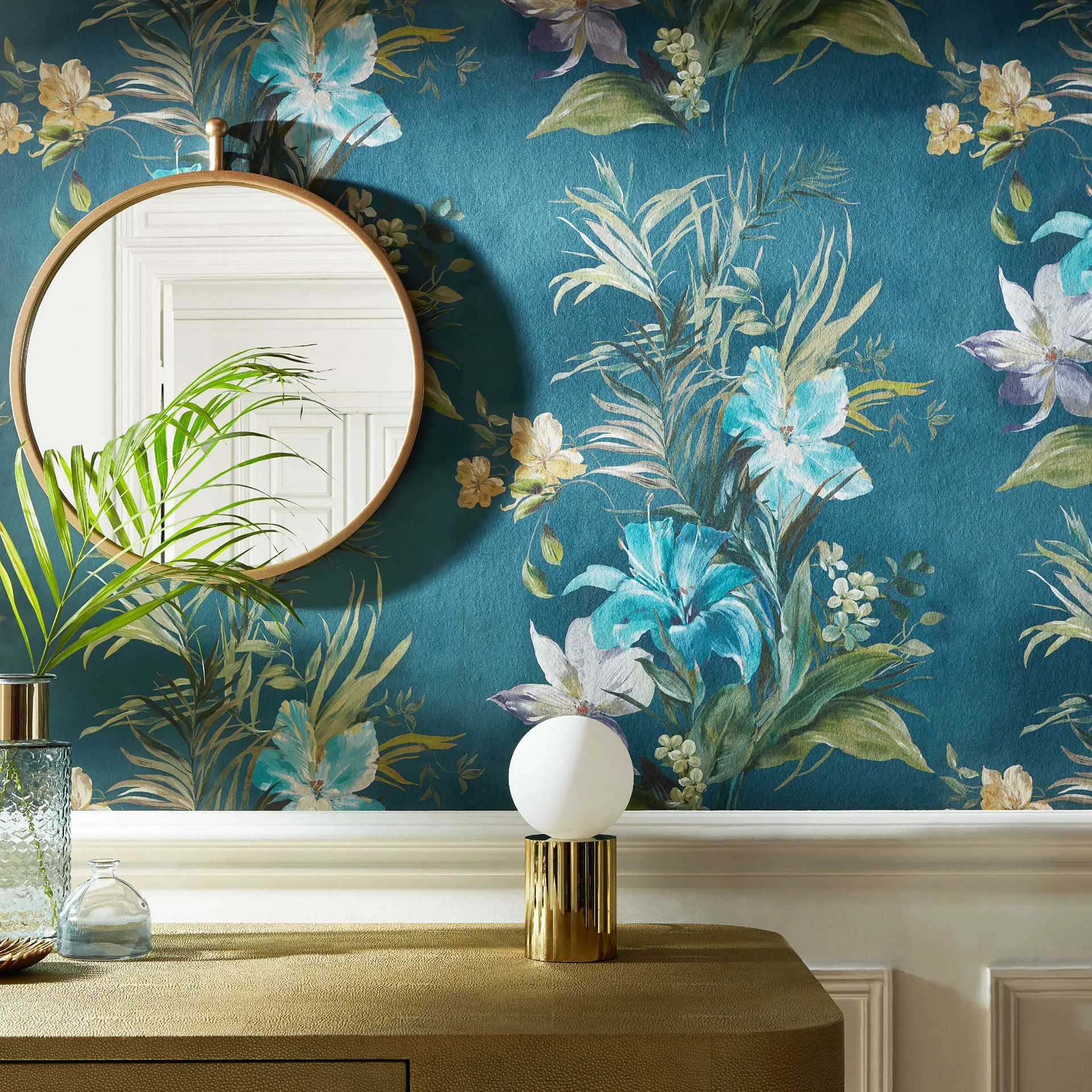A blue floral wallpapered feature wall, with a mirror and table