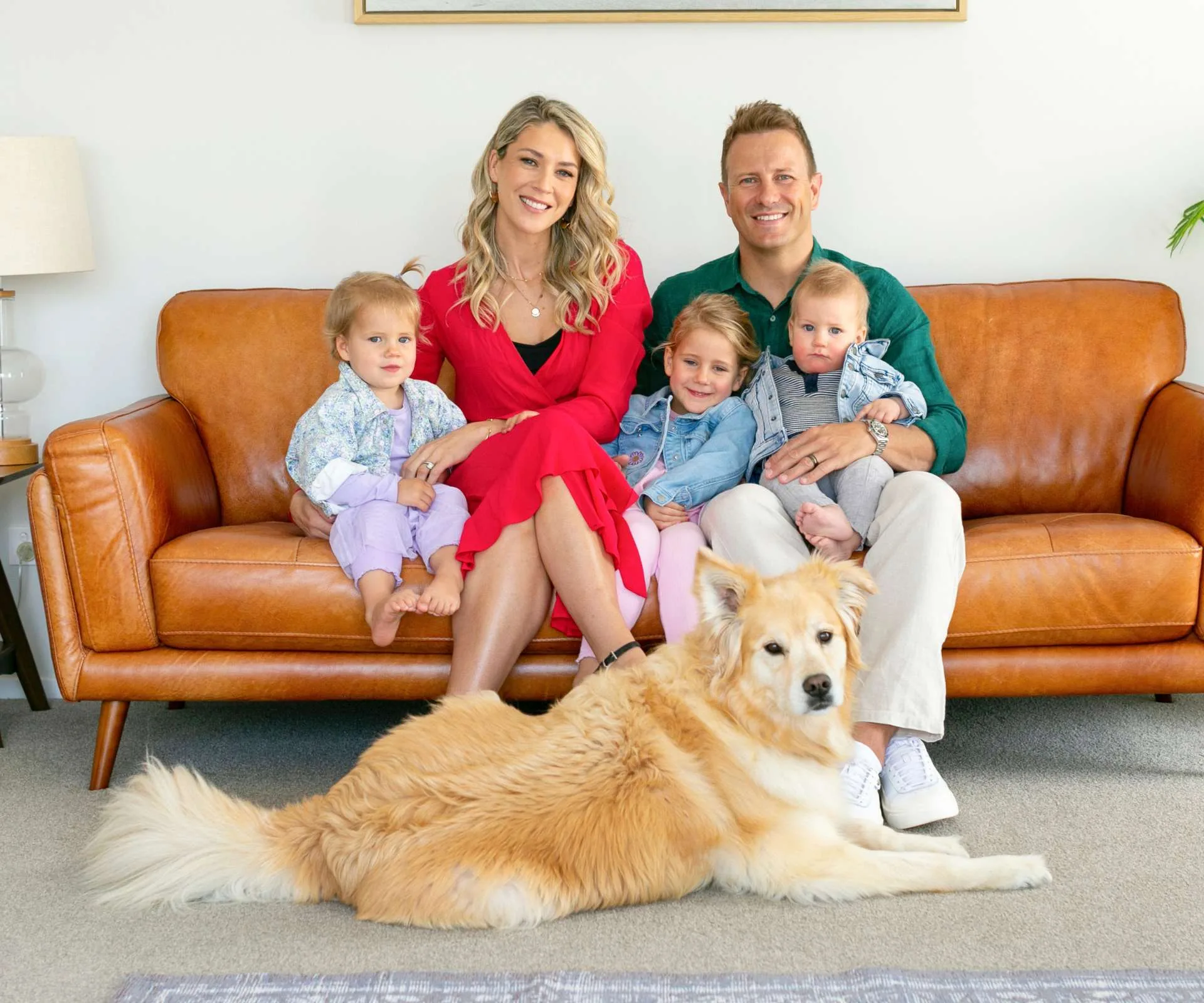 Neil Wagner sitting on a leather couch with his wife, kids and dog