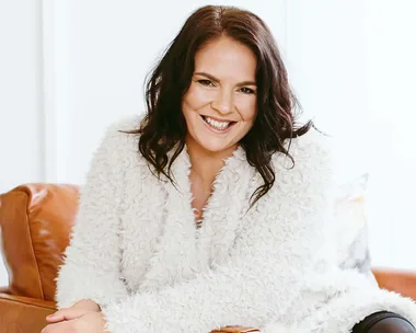 Jacqueline Bublitz smiling on a brown leather armchair