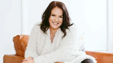 Jacqueline Bublitz smiling on a brown leather armchair