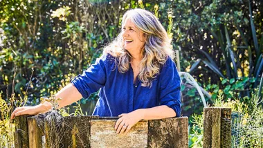 Wendyl Nissen leaning on a wooden fence