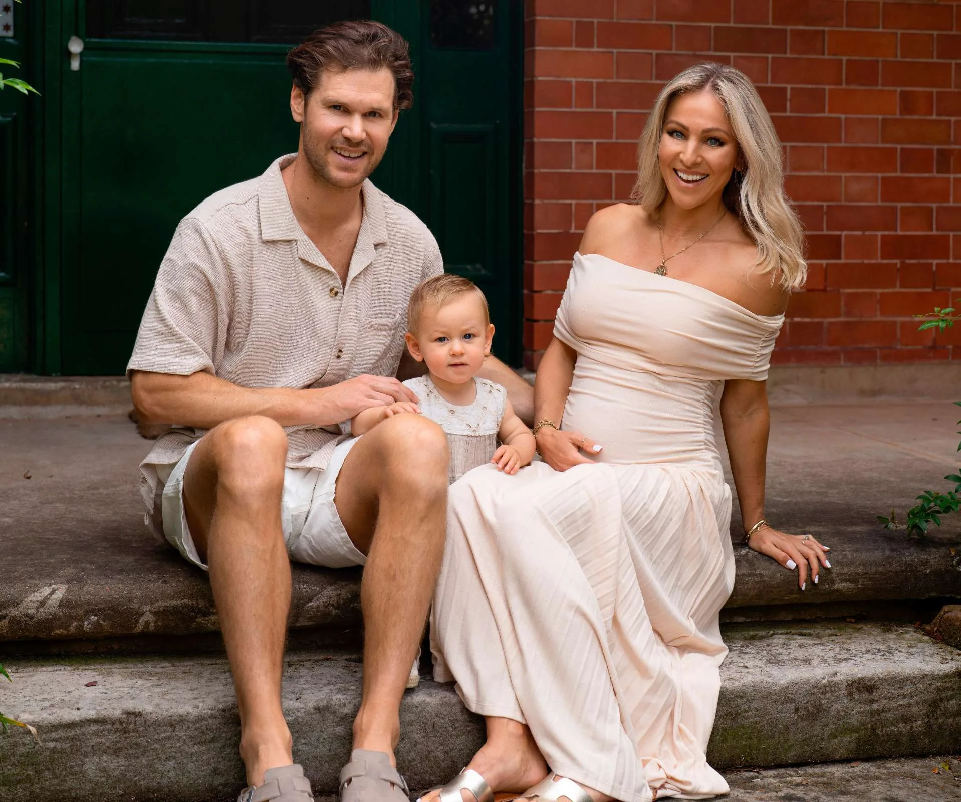 A pregnant Kerry-Lee Dewing sitting on some concrete steps with her family