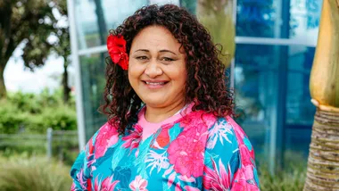 Linda in a pink and blue sweatshirt with a red flower behind her ear