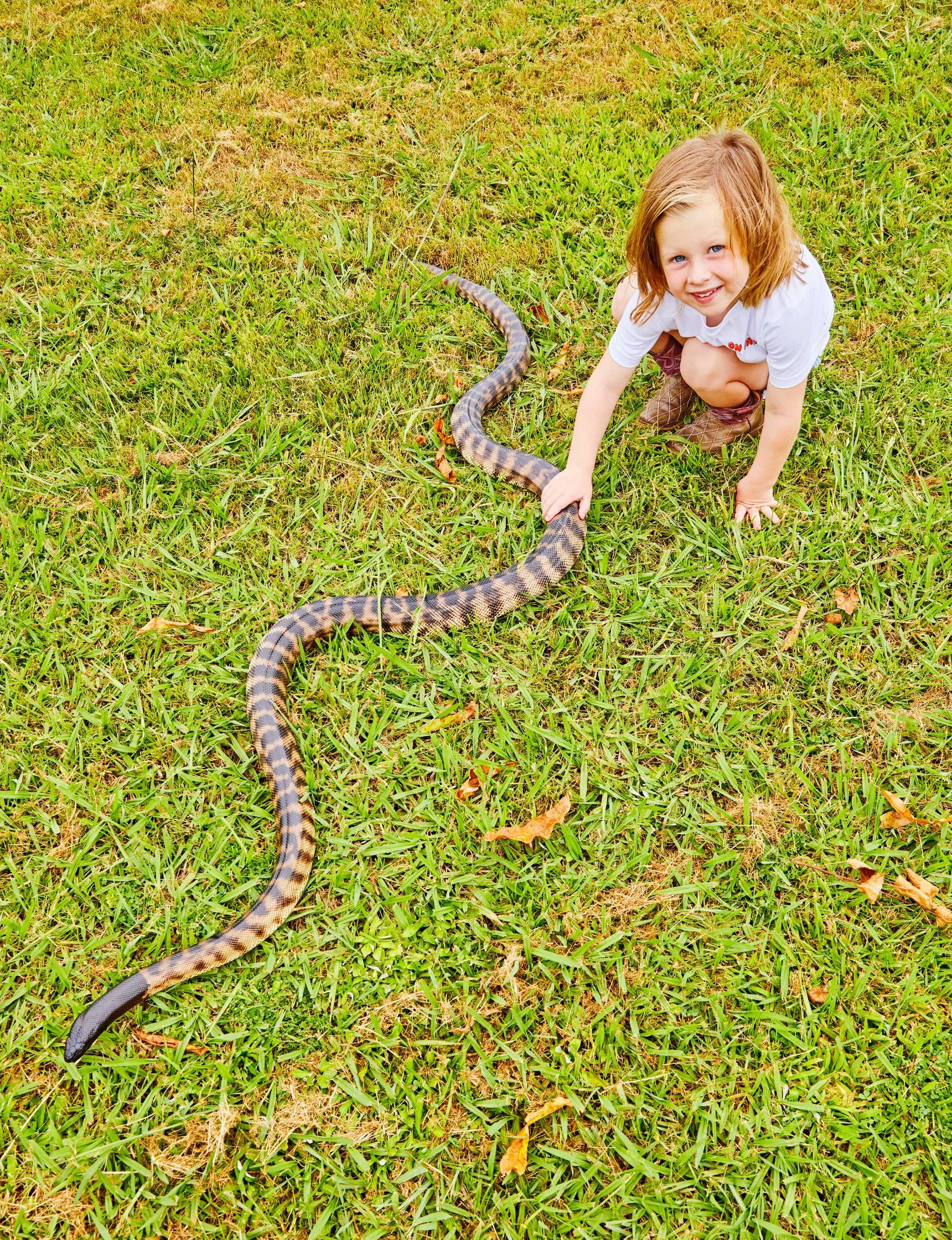 Ashlee holding a snake on the ground