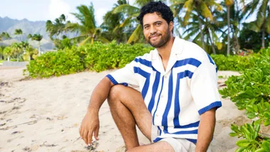 Alex Tarrant sitting on a beach