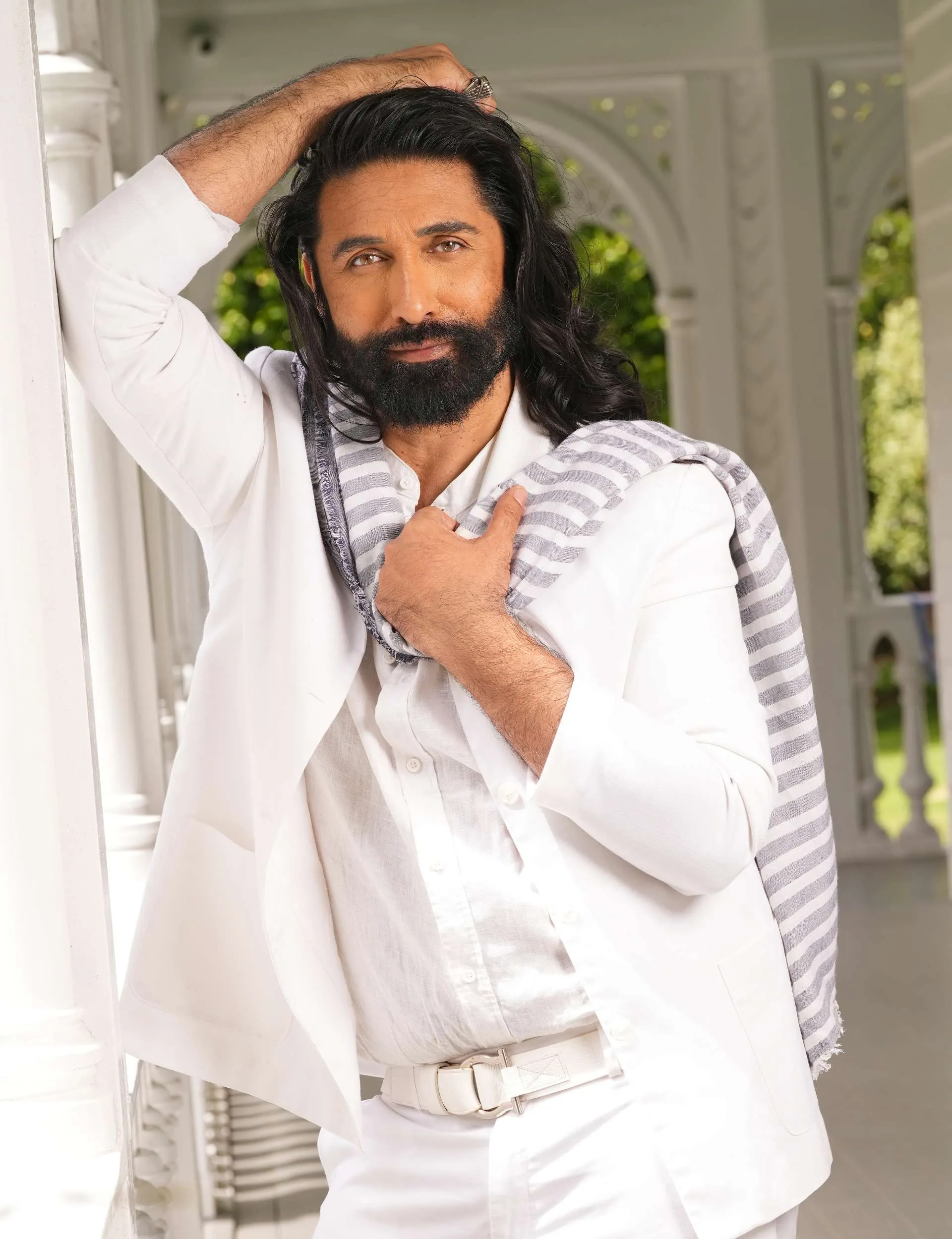 Colin Mathura-Jeffree wearing white, leaning on a white wall