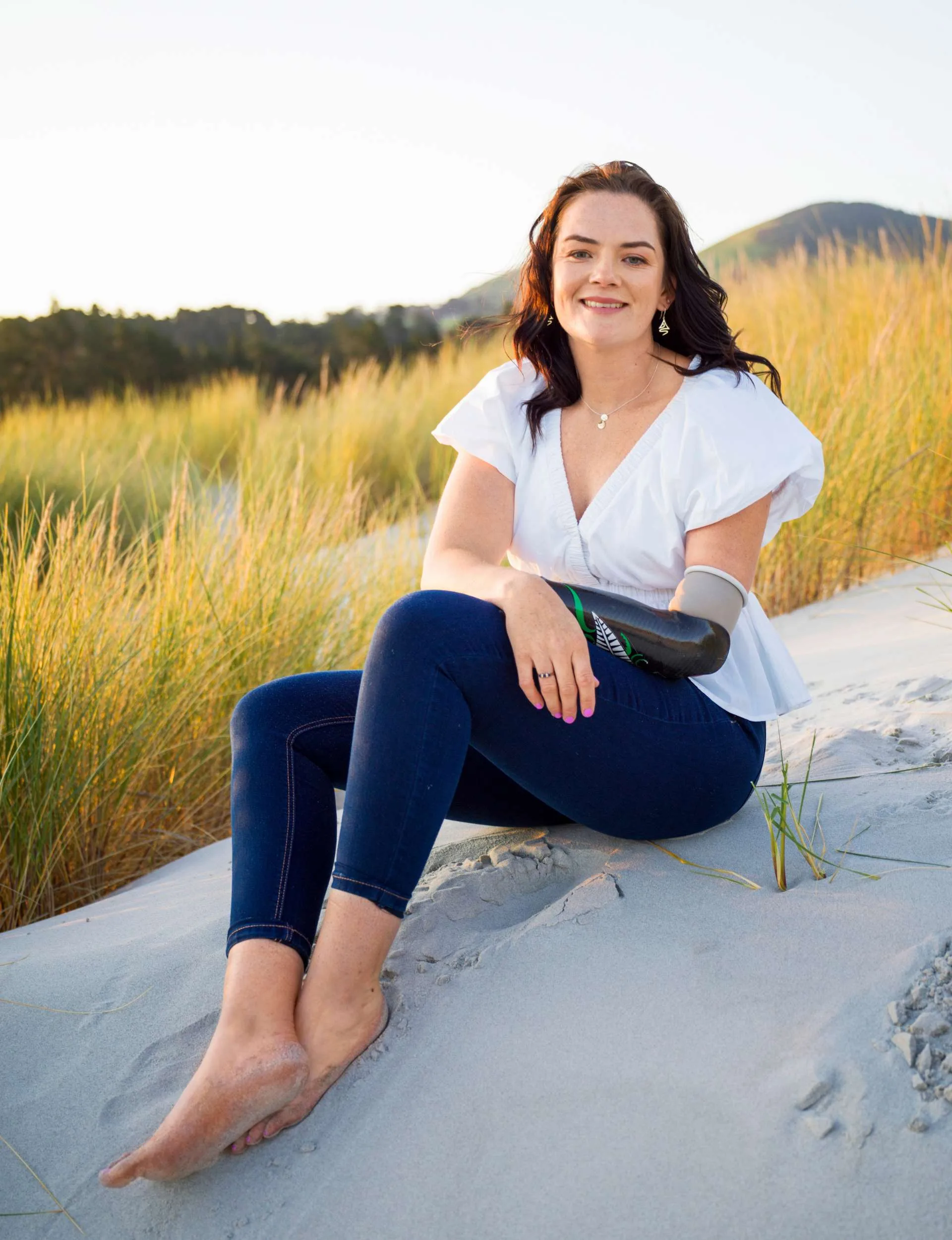 Holly Robinson showing off her ring while sitting on a sand dune