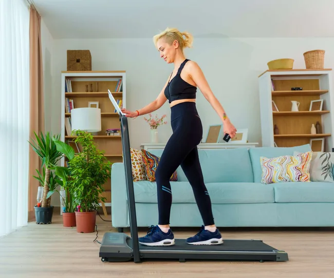 A woman walking on a treadmill at home before her workout