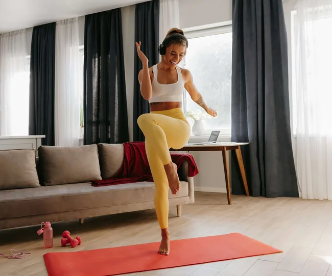 A woman jumping on a yoga mat at home