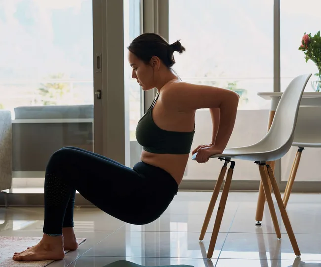 A woman doing chair dips at home