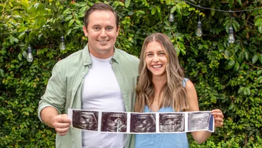 Kiwi couple Emma and Travis holding up the ultrasound images of their surrogate baby