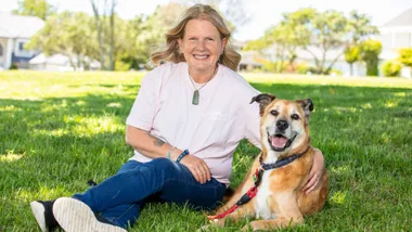 Karen Barnett sitting on some grass with her dog
