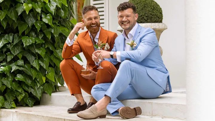 Jono Trenberth and Josh Martyn sitting together on outdoor steps at their wedding