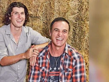 Shannon Noll sitting on a hay bale with his son