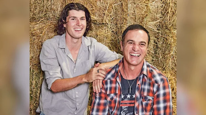 Shannon Noll sitting on a hay bale with his son