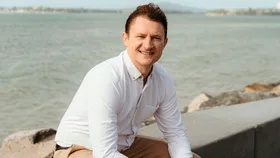 Hamish Williams sitting on a ledge near a beach