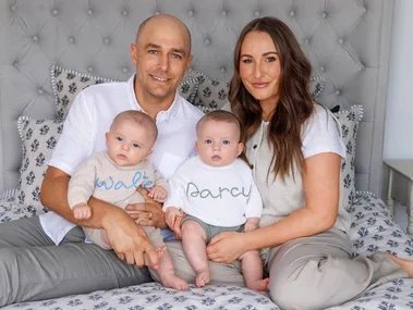 Bella and Julyan sitting on their bed with twins Walter and Darcy