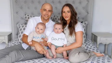 Bella and Julyan sitting on their bed with twins Walter and Darcy