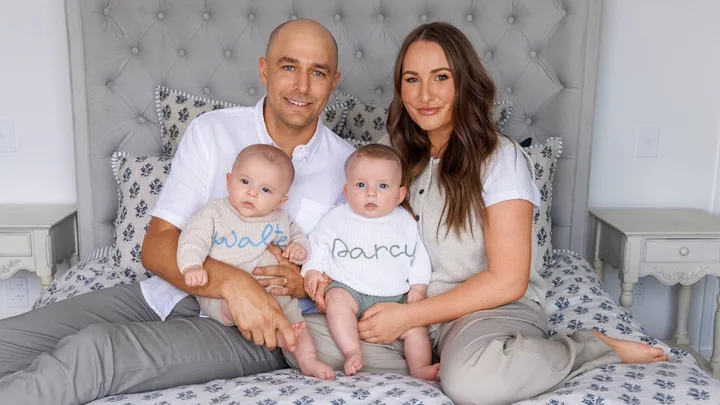 Bella and Julyan sitting on their bed with twins Walter and Darcy