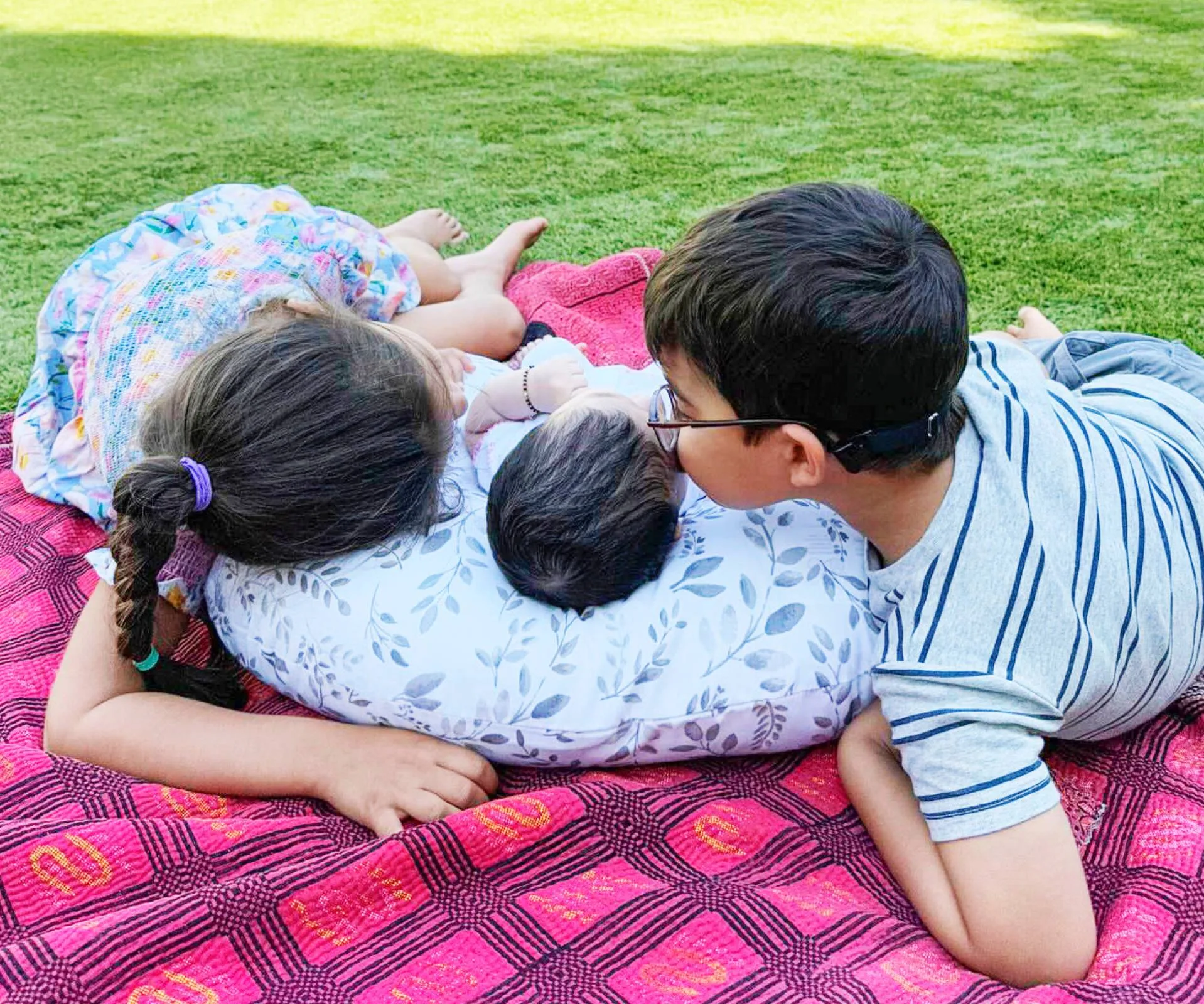 Siblings kissing the head of the babies born in 2024