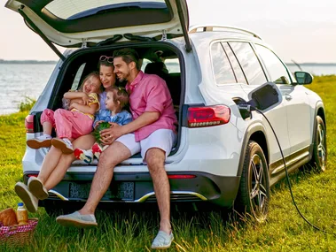 A family all sitting in the boot of their car playing games on a break from their road trip