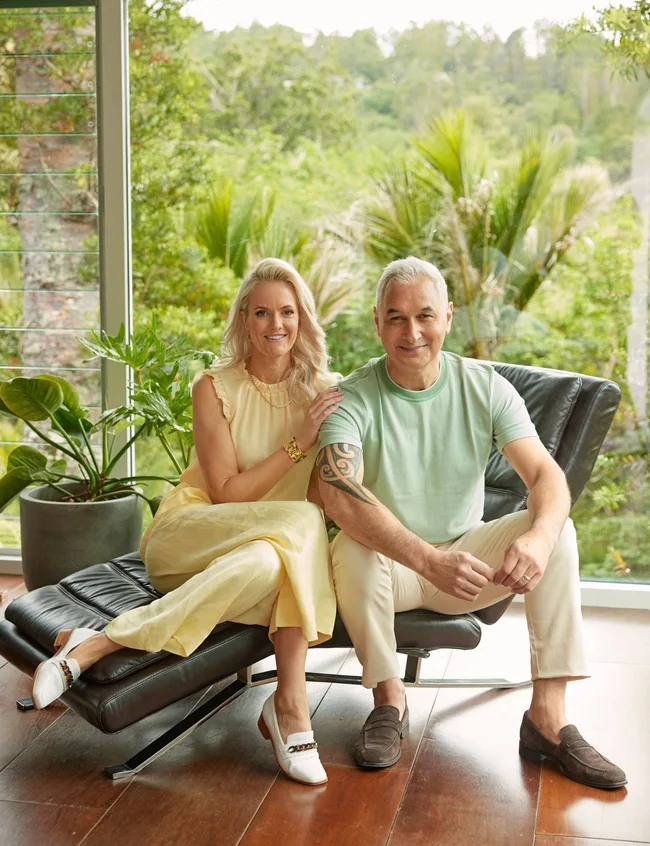 Man and woman sitting on couch with forrest behind them.