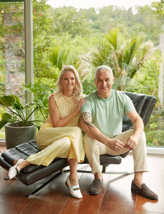 Man and woman sitting on couch with forrest behind them.