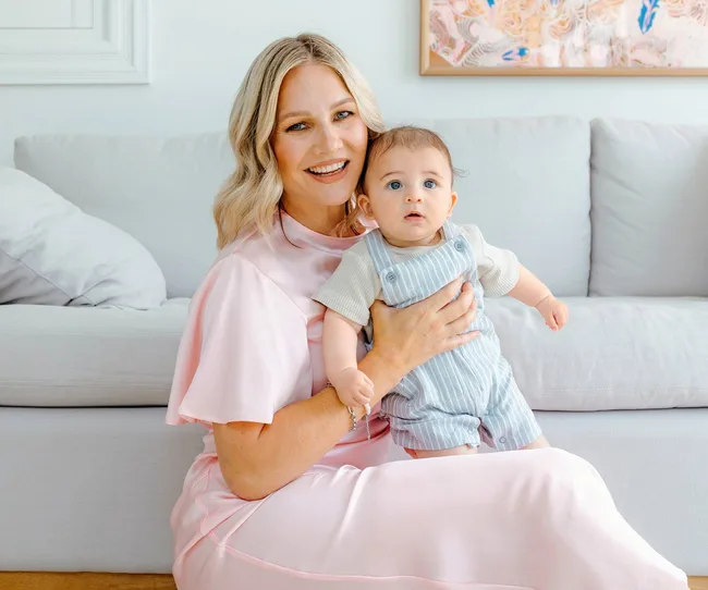 Woman holding baby wearing lilac dress