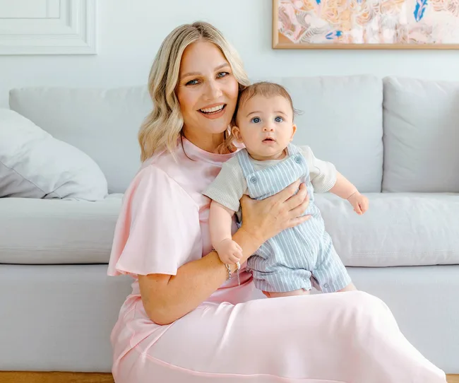 Woman holding baby wearing lilac dress