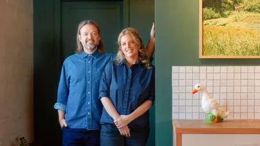 A couple weraing denim shirts with a a green wall