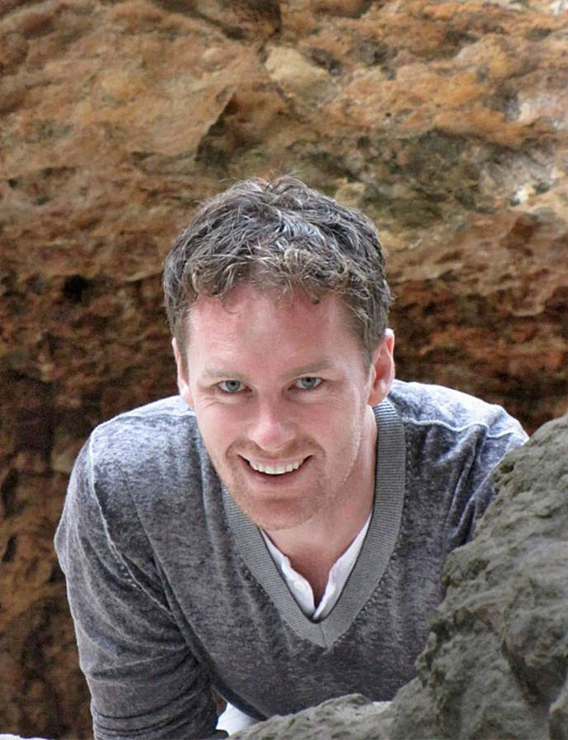 Man smiling wearing grey sweater.