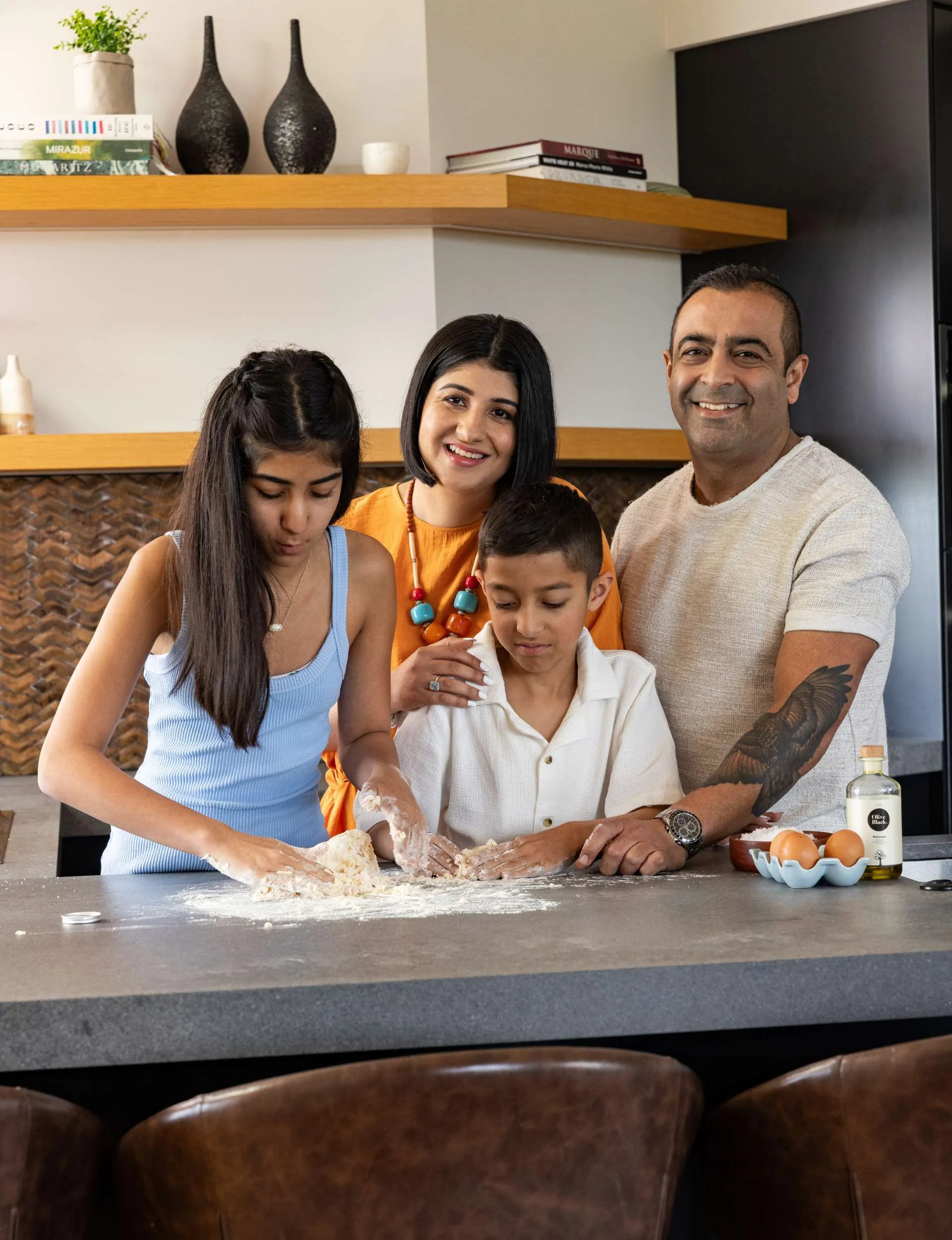 Indian family in kitchen while the children make bread