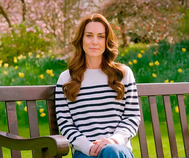 Kate MIddleton sitting on a park bench with a garden