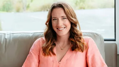 Anna Taylor wearing pastel pink while sitting on a couch