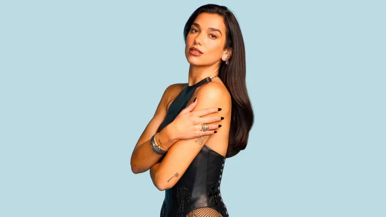 Dua Lipa in front of a light blue backdrop