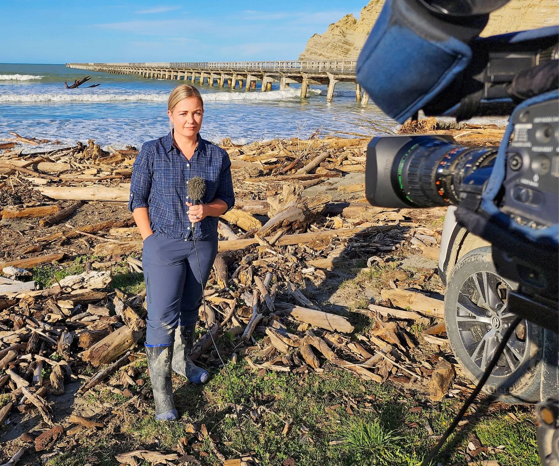 Alexa Cook in front if the camera, reporting on Cyclone Gabrielle from a beach