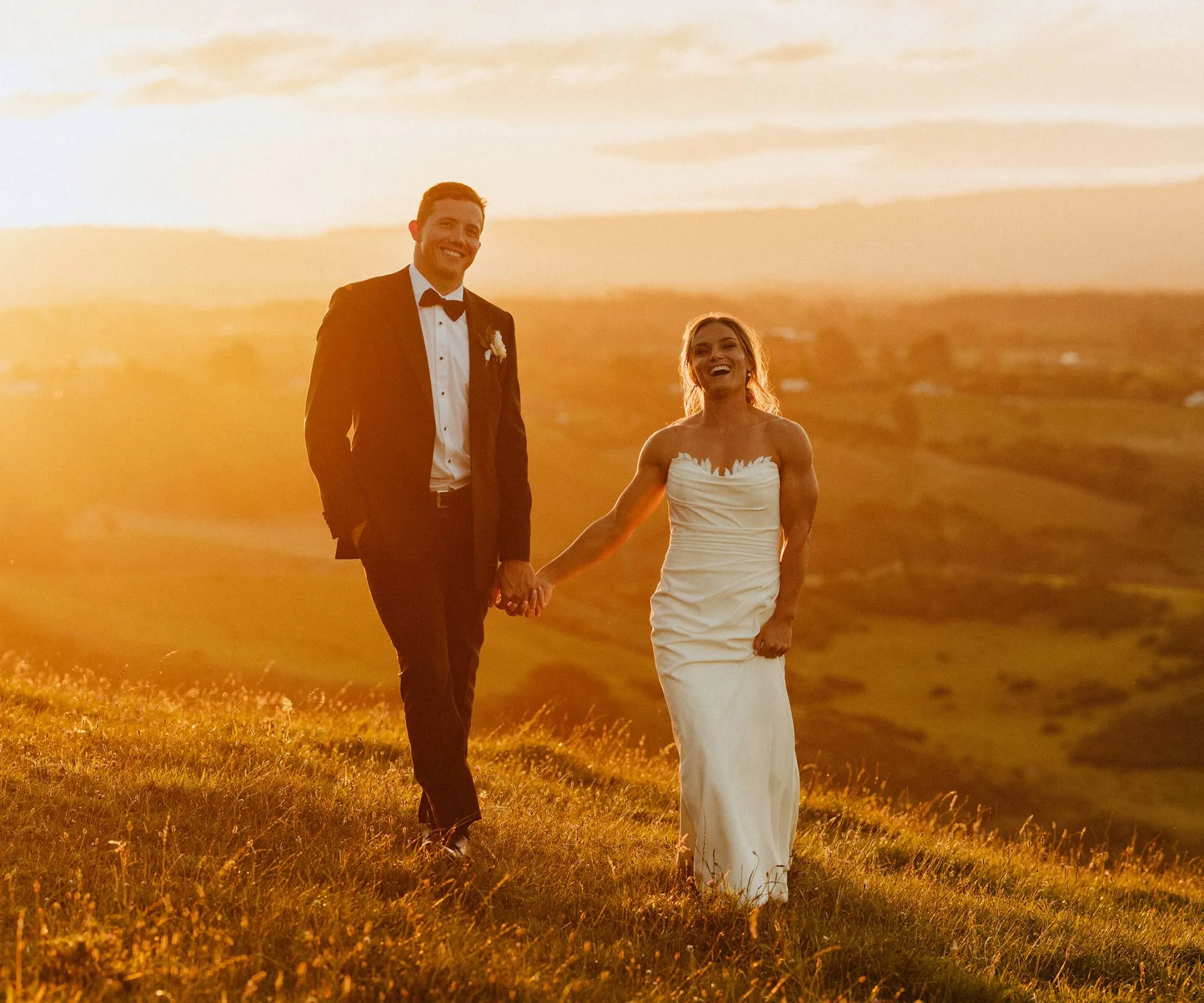 Michaela and Michael walking hand in hand along a ridgeline at sunset on their wedding day