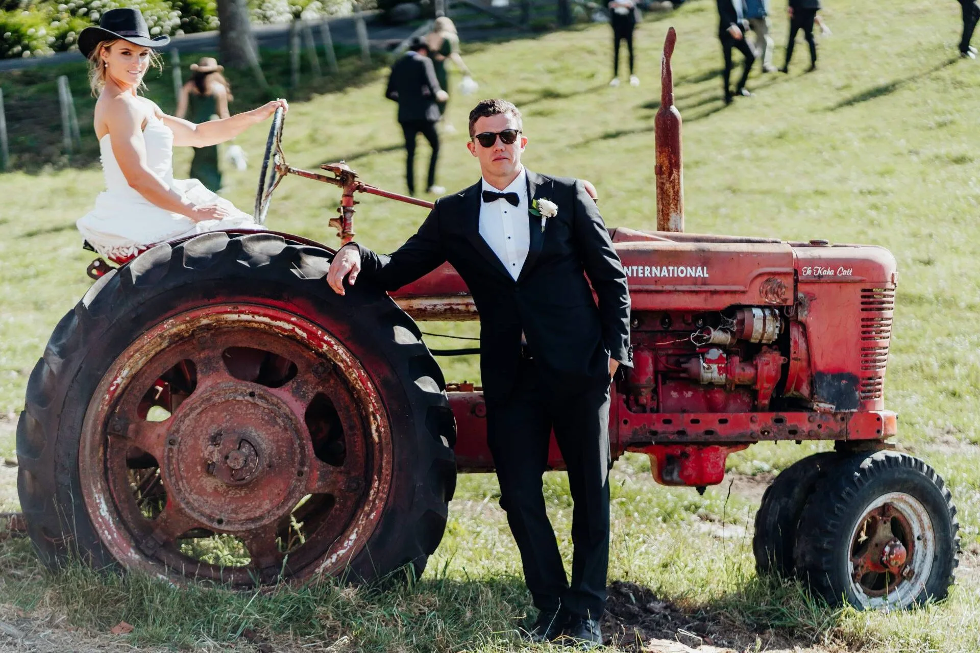 Michaela behind the steering wheel of an old and rusty tractor, Michael leaning against the side of it