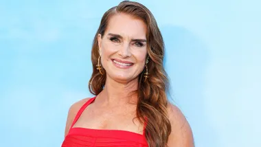 Brooke Shields in front of a blue backdrop at an event