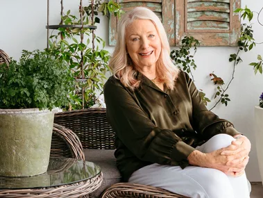 Robyn Martin sitting on a chair in front of potted indoor plants