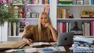 Collette Dinnigan sitting at a desk in front of a giant bookshelf