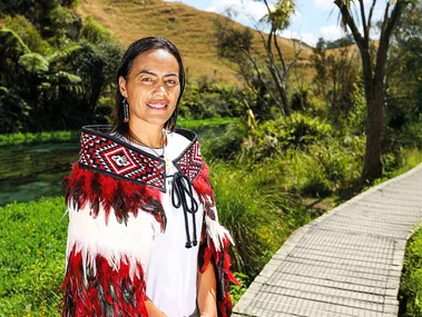 Woman wearing a Maori Korowai standig near a lake