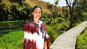 Woman wearing a Maori Korowai standig near a lake