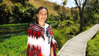 Woman wearing a Maori Korowai standig near a lake