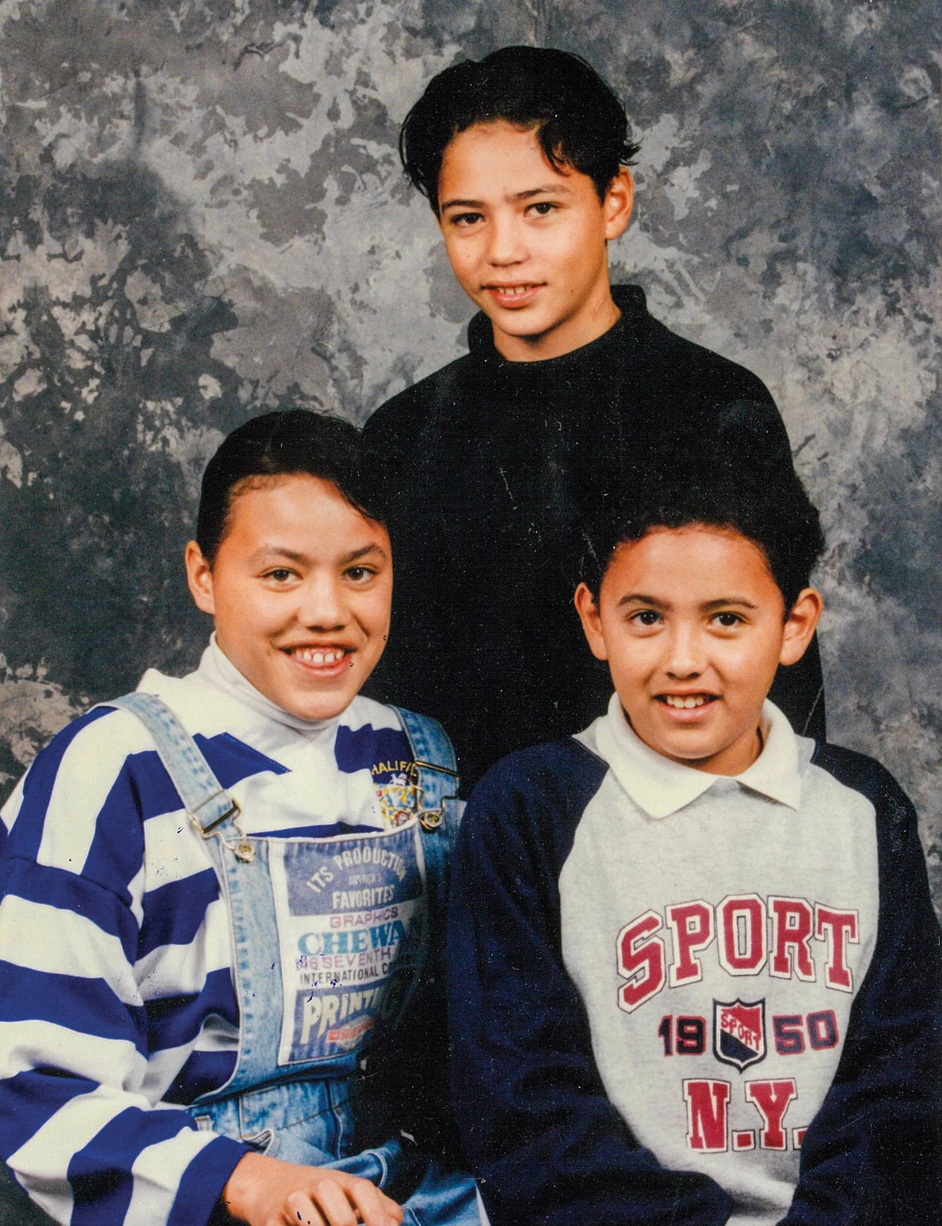 Children in the 80s sitting in front of a grey background